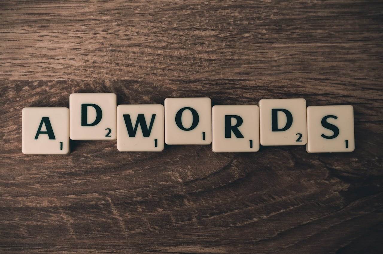Home Scrabble tiles spelling AdWords on a wooden surface, symbolizing digital marketing concepts.